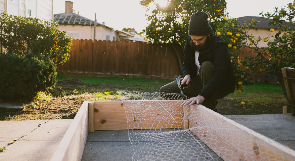 Person building raised bed garden with chicken wire mesh