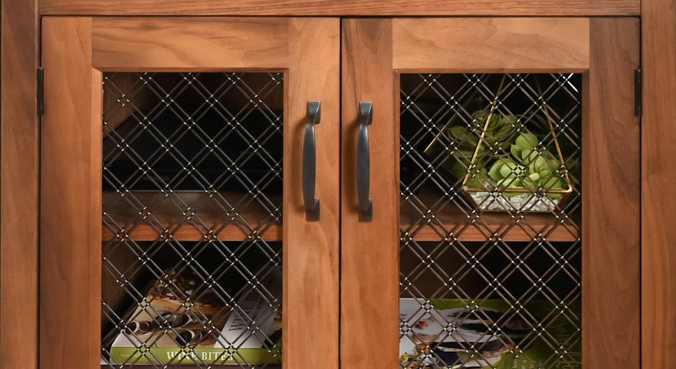 Wood cabinet with dishes and double diagonal, stainless steel wire mesh inserts.