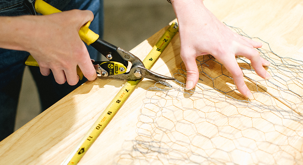 person cutting chicken wire mesh for a frame