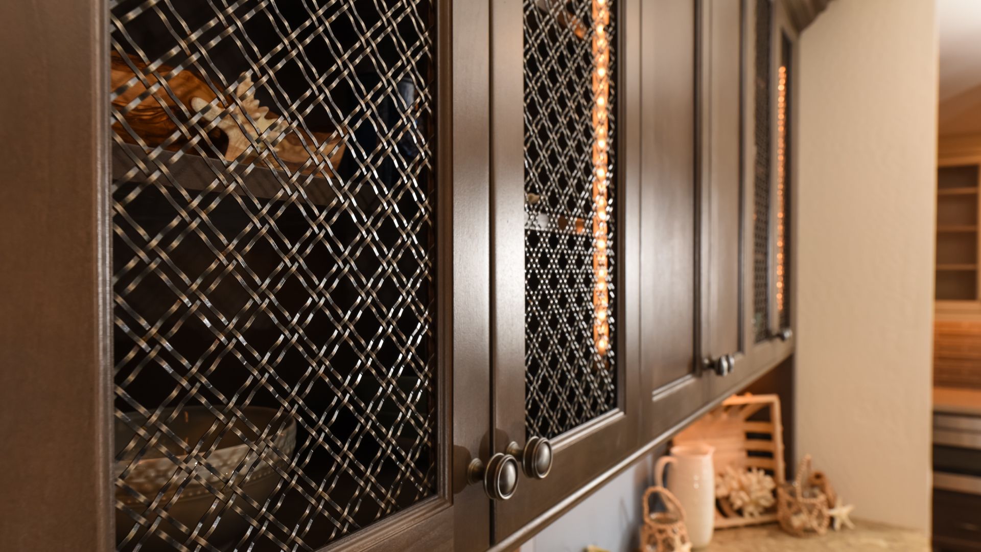 Woven wire mesh on dark brown wooden cabinet doors.