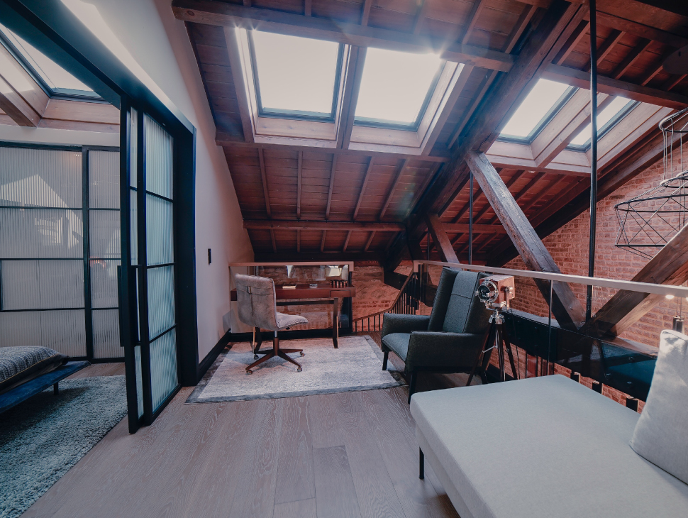 A residential attic with with a home office, bedroom, and skylights.
