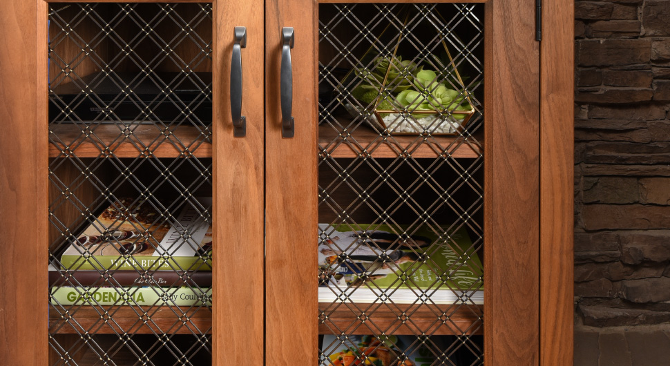 Wood bookcase with bronze wire mesh cabinet door inserts.