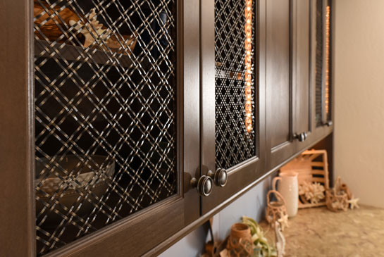 Wood cabinet with double diagonal bronze mesh inserts in the cabinet doors.