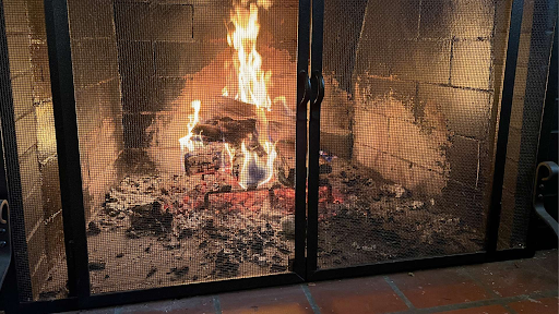 A fireplace with wire mesh screen doors