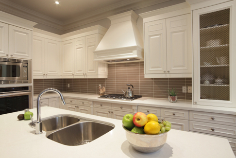 Newly designed kitchen with a granite island, double sinks, gas range, and gorgeous with cabinets with decorative wire mesh inserts in the doors. 