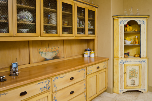 Country kitchen with warm wood accents and hand-painted cabinets that feature decorative wire mesh inserts.