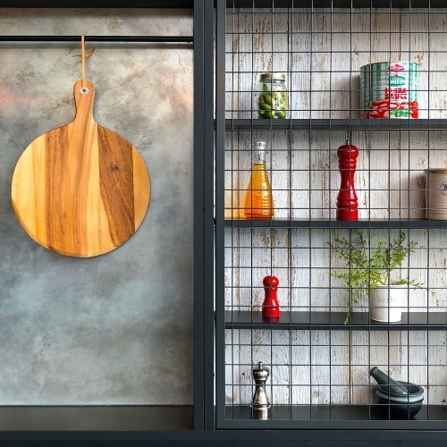 Stylish kitchen shelves with wire mesh fronts, displaying plants, collectibles, and a wood cutting board.